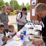 Youngsters Asher and Kira Clark debate their choices in the car show voting, while volunteer Anne Smarsh finds something to reward their efforts. The family, including Amanda and Bryce Clark in the background, had just finished the 1K race before visiting the car show.                                Carol Ladwig/Staff Photo