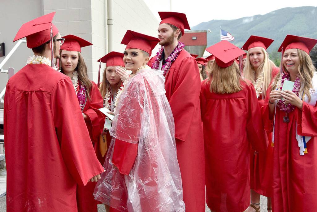Hunter Dow, swathed in a raincoat, smiles before graduation began Friday night.                                Carol Ladwig/Staff Photo