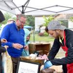 Sara and Mike Ruhland sample some of new vendor, Saucy Mama&rsquo;s products at opening day of the farmers market.                                Carol Ladwig/Staff Photo