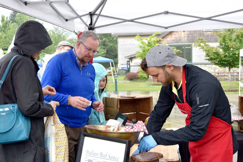 Sara and Mike Ruhland sample some of new vendor, Saucy Mama&rsquo;s products at opening day of the farmers market.                                Carol Ladwig/Staff Photo
