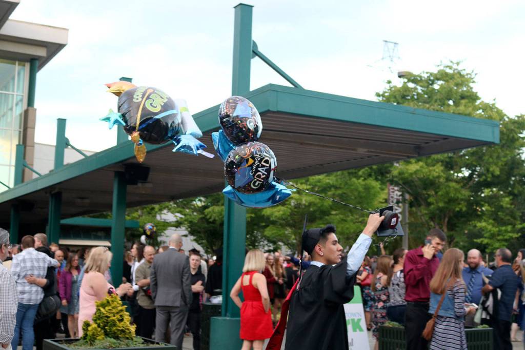 Alex Zarco carries bunch of graduation balloons out of the venue after the ceremony.                                (Evan Pappas/Staff Photo)