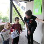 Children&rsquo;s Librarian Jenifer Loomis leads Lily and Logan Weathers to the next exhibit after they picked out their coloring books.                                (Evan Pappas/Staff Photo)