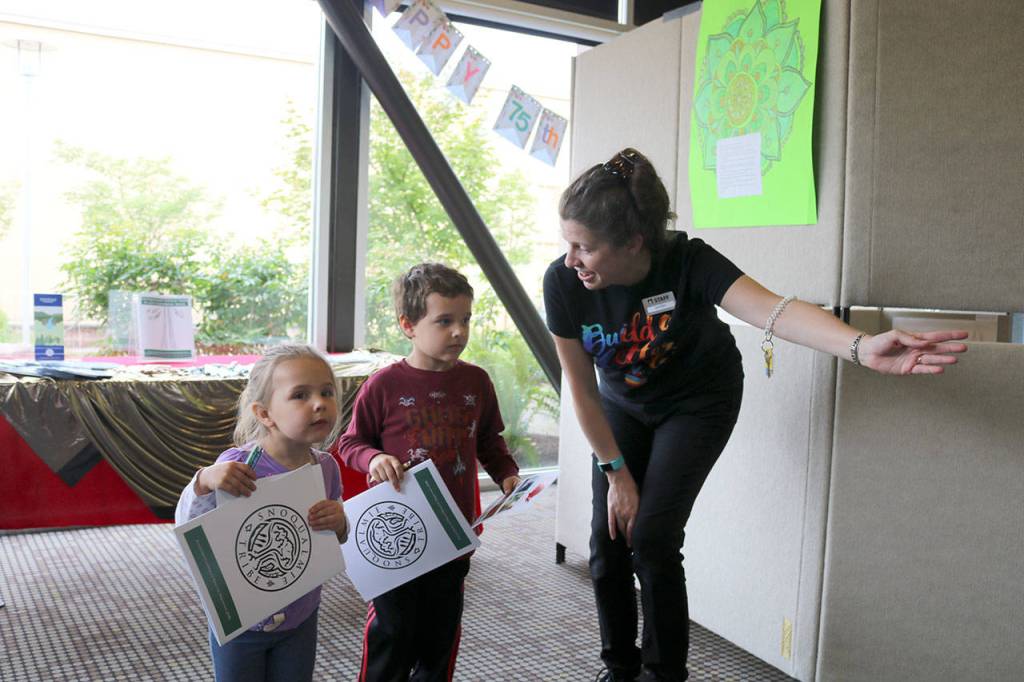 Children&rsquo;s Librarian Jenifer Loomis leads Lily and Logan Weathers to the next exhibit after they picked out their coloring books.                                (Evan Pappas/Staff Photo)