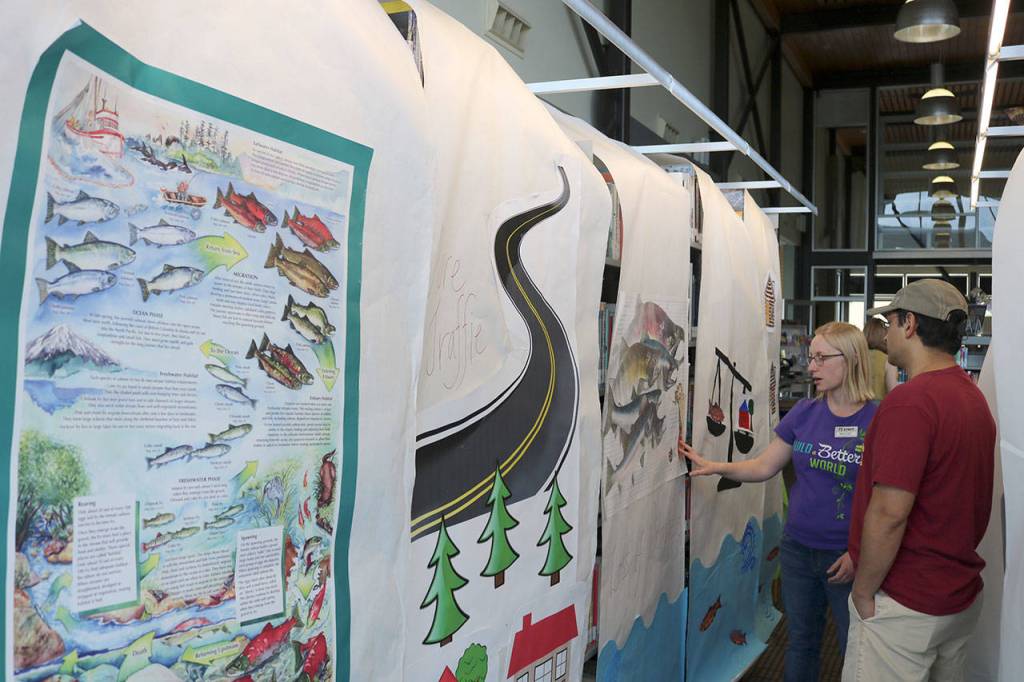Maggie Wong tells a parent about the event and shows the materials created by teen volunteers for the library.                                (Evan Pappas/Staff Photo)