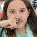 Ava Willard makes the most of her mustache henna tattoo at the 2016 Block Party.                                (Photo by Mary Miller)