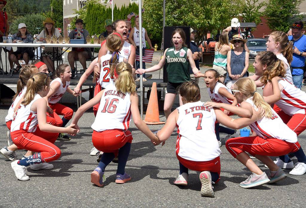 Softball all-stars lead a cheer in front of the parade stage. (Carol Ladwig Staff Photo)