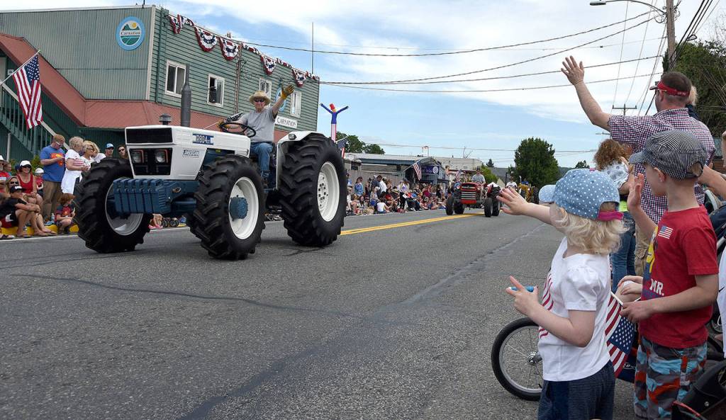 Children wave excitedly at a Lamborghini tractor in the parade. (Carol Ladwig Staff Photo)