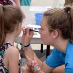 Sarah Goodspeed, volunteering at the Encompass booth, paints a heart on Kaethyn Franklin&rsquo;s cheek. Carol Ladwig/Staff Photo