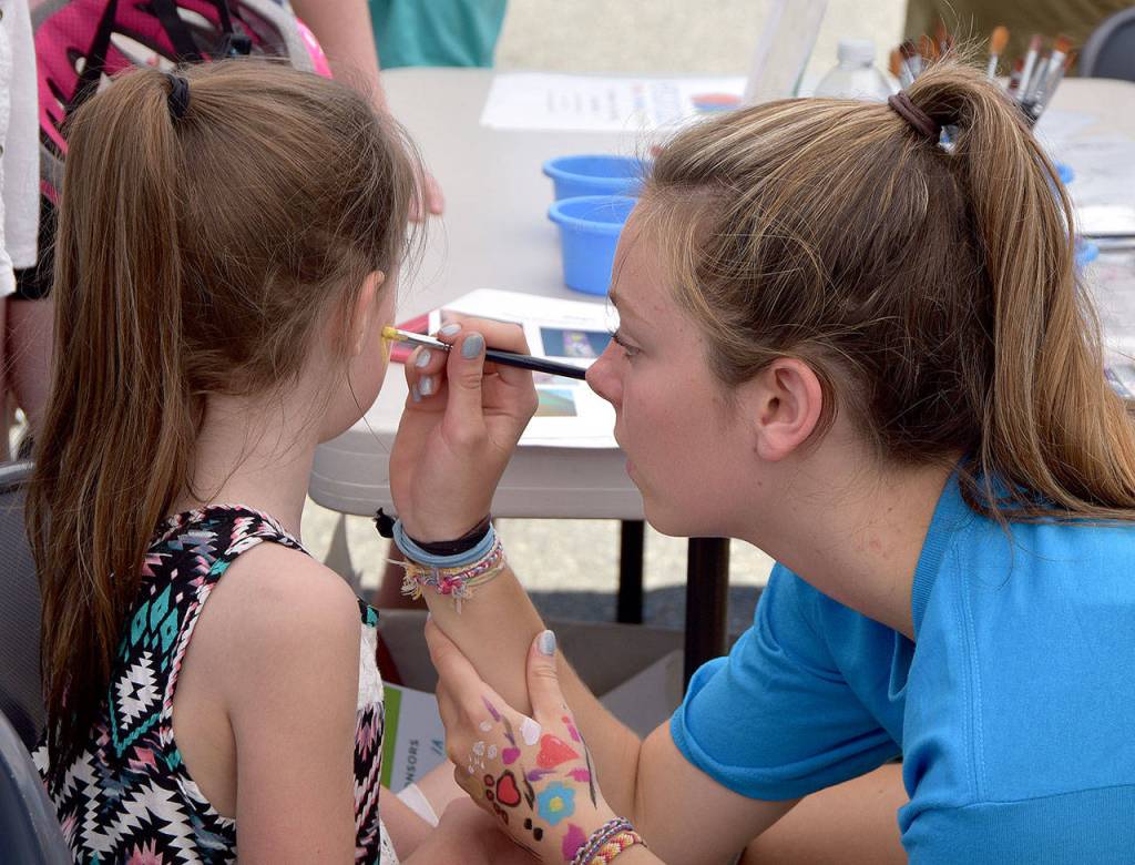 Sarah Goodspeed, volunteering at the Encompass booth, paints a heart on Kaethyn Franklin&rsquo;s cheek. Carol Ladwig/Staff Photo