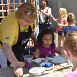 Sara Lewis gets help from a Mount Si Artist Guild volunteer to start painting her masterpiece, a puzzle piece for a community collage. Carol Ladwig/Staff Photo
