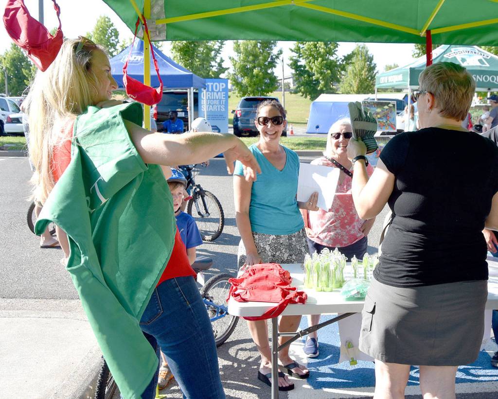 Kaley Seidenstucker, left and April Brown discuss CERT training with guests at the event Tuesday evening. Seidenstucker volunteered to model the stylish green vest that CERT students receive when they complete the class and sign up as volunteer emergency responders.                                (Carol Ladwig/Staff Photo)
