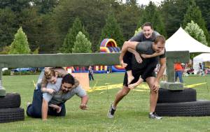 Chris and Jamie Teteak of North Bend smile hugely as they clear an obstacle, pursued by Alex Brewer and Lilly Knotts of Snoqualmie, in Sunday&rsquo;s wife-carrying contest.                                (Carol Ladwig/Staff Photo)