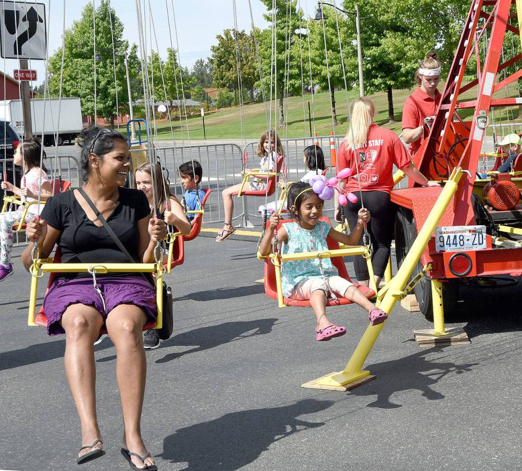 Families enjoy a ride on the swings. (Carol Ladwig/Staff Photo)