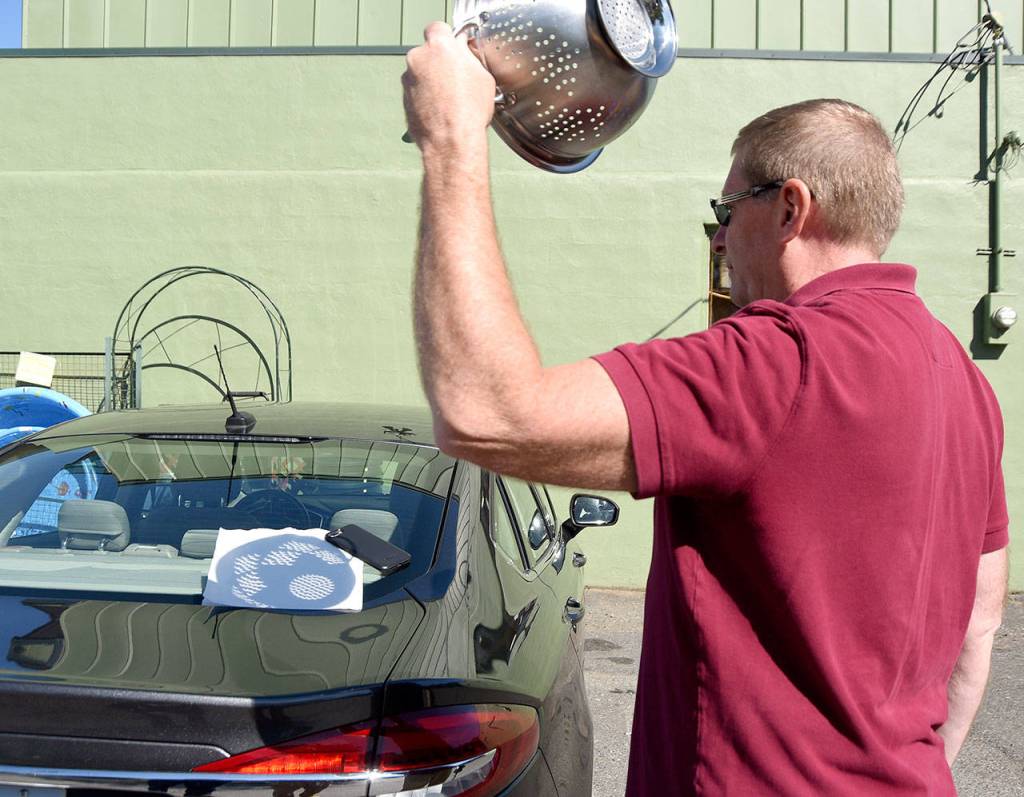 Tim Smith, a visiting, science teacher from Massachusetts, used a colander to make dozens of pinhole-projection eclipses.                                (Carol Ladwig/Staff Photo)