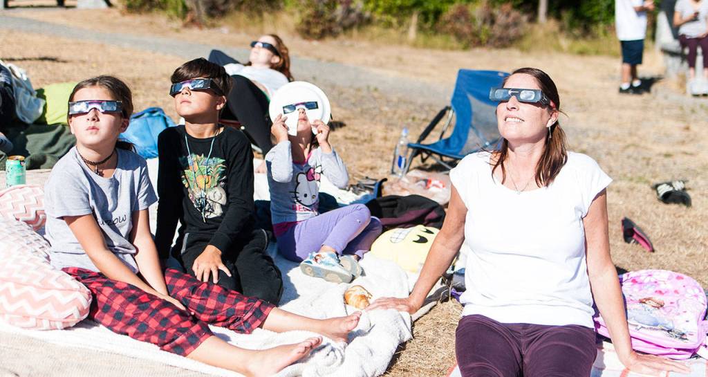 At Snoqualmie Point Park, Kathy White watches the solar eclipse with her grandchildren, Quin and Anja.                                (Photo courtesy of Kristin Tetuan)