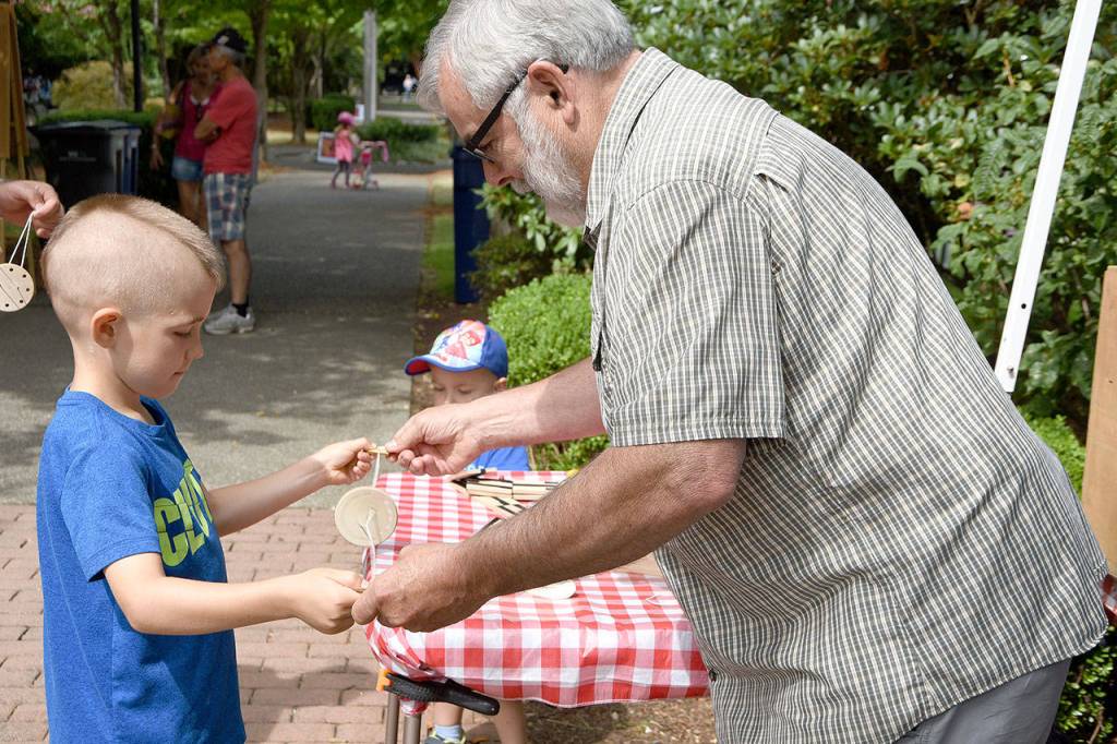 Dick Kirby, with the Snoqualmie Valley Historical Museum booth, helps a youngster named Matthew to get started with a toy called the buzz saw.                                (Carol Ladwig/Staff Photo)