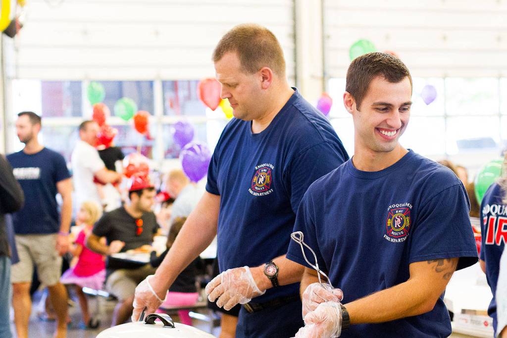 Snoqualmie Firefighters Mike Bailey and Tanner Webb serving pancakes, bacon and doughnuts.                                (Jessie Koon Photo)
