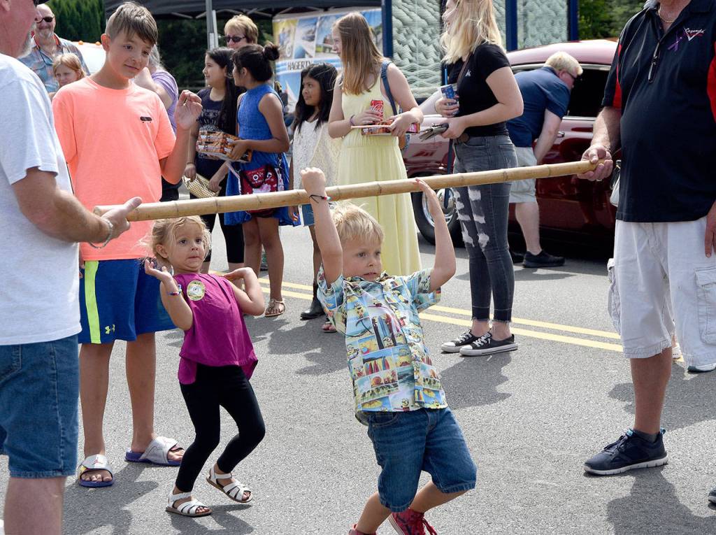 Children go to great lengths to bend under the limbo stick during the fun awards games at the Legends Car Show Sunday in Snoqualmie.                                (Carol Ladwig/Staff Photo)