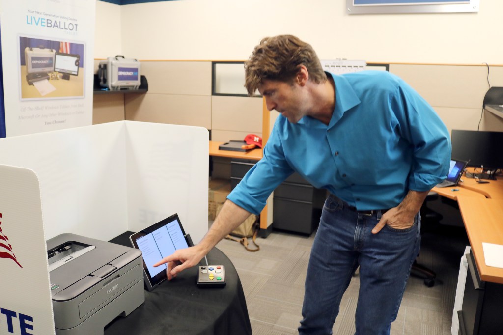Evan Pappas/Staff Photo                                Bryan Finney, owner of Democracy Live, demonstrates how to use his company&rsquo;s LiveBallot Tablet ballot software, which provides audio information on the ballot for voters who can&rsquo;t read the screen.