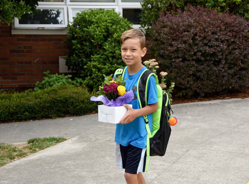 Duncan Maynard carries a flower arrangement for his teacher as Fall City Elementary School started the school year on Wednesday, Aug. 30. He starts the fourth grade. (Carol Ladwig/Staff Photo)
