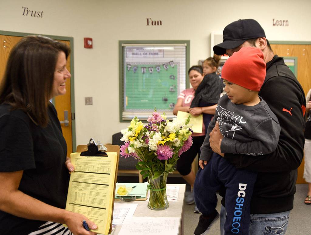 Tony Martinez, holding his 2-year-old son Troy, talks with Fall City Elementary School office staff as school starts for the year. &ldquo;I used to go to this school,&rdquo; he said. Now, he was there to drop off his daughter, Amanda. (Carol Ladwig/Staff Photo)