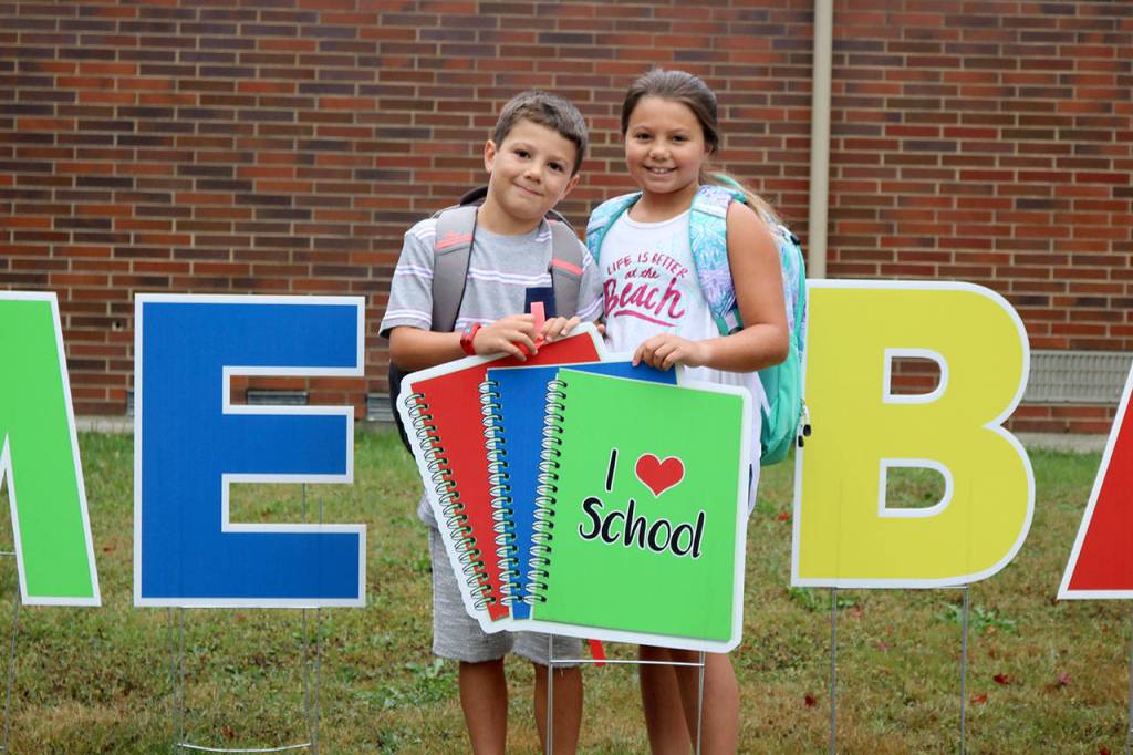 Gavin and Evie Wilson stand by the &ldquo;I love school&rdquo; sign while their mom gets a picture before classes begin. (Evan Pappas/Staff Photo)