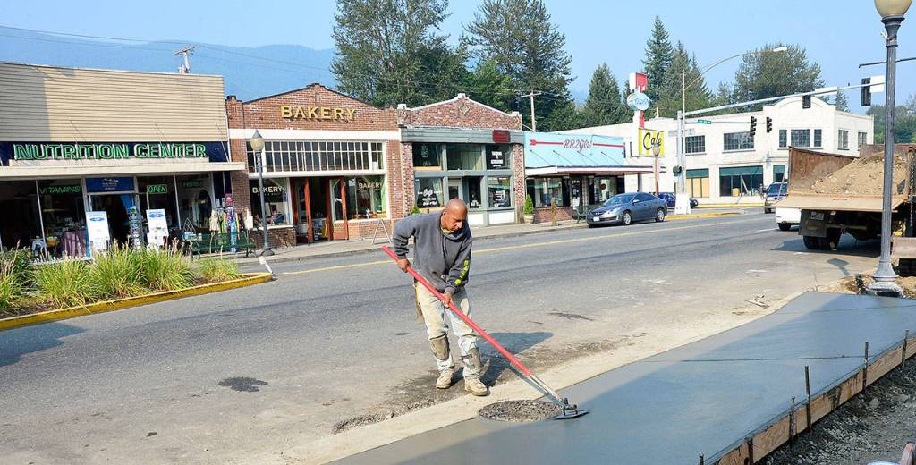 A concrete worker smooths out the new sidewalks poured two weeks ago as part of the North Bend downtown plaza project, another effort by the city to revitalize downtown. The block pictured here, along with businesses on the opposite side of the street, make up the city&rsquo;s Historic Downtown District. (Photo courtesy of Mary Miller)