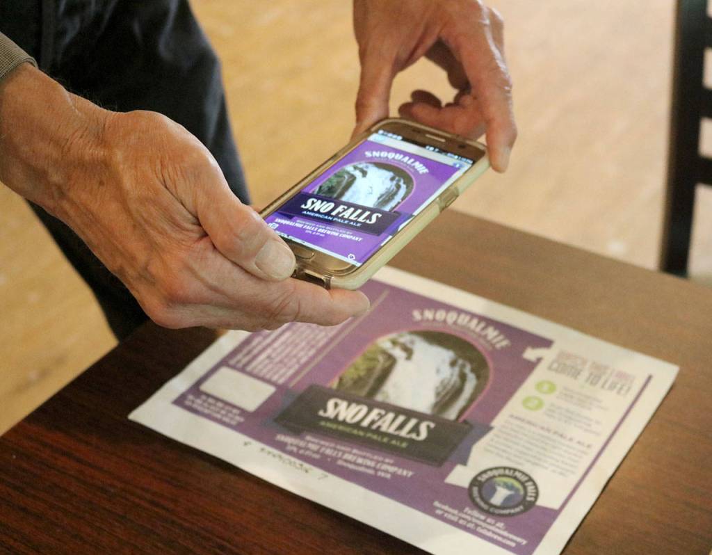 Dave Eiffert, general manager of the Snoqualmie Brewery and Taproom, demonstrates the augmented reality animation on the labels for the brewery&rsquo;s new pale ale. (Evan Pappas/Staff Photo)