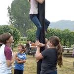 Clara Aierstock, 7, gets help from Lola Petty, 10, as she attempts to climb a greased pole at Jubilee Farm during the Sno Valley Tilth Farm Faire Saturday. Both girls are from Issaquah. (Carol Ladwig/Staff Photo)