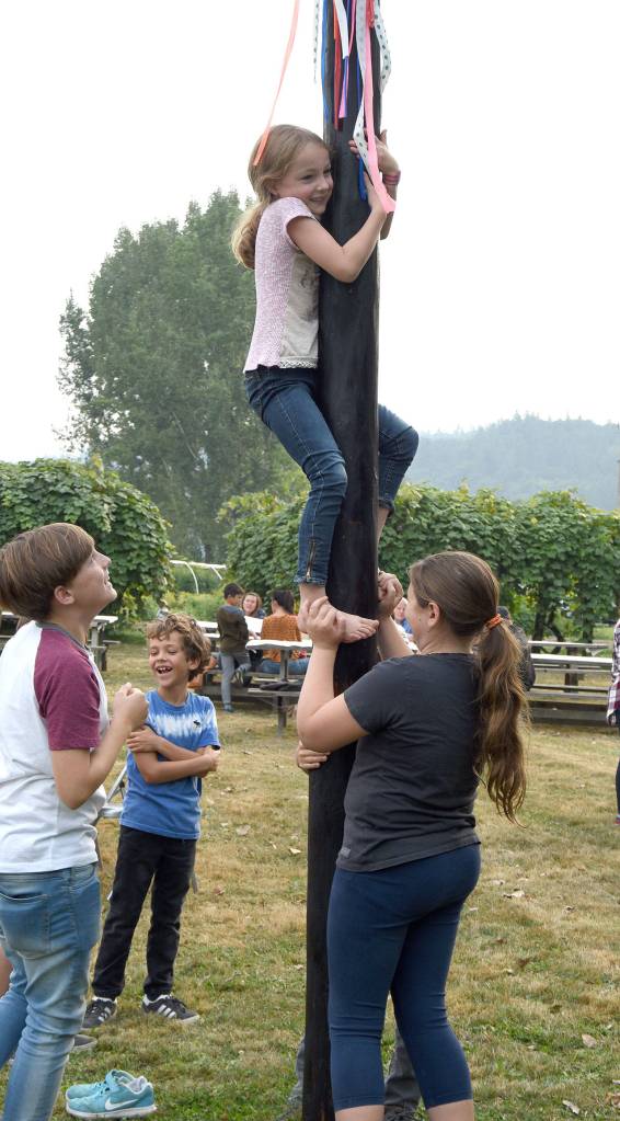 Clara Aierstock, 7, gets help from Lola Petty, 10, as she attempts to climb a greased pole at Jubilee Farm during the Sno Valley Tilth Farm Faire Saturday. Both girls are from Issaquah. (Carol Ladwig/Staff Photo)