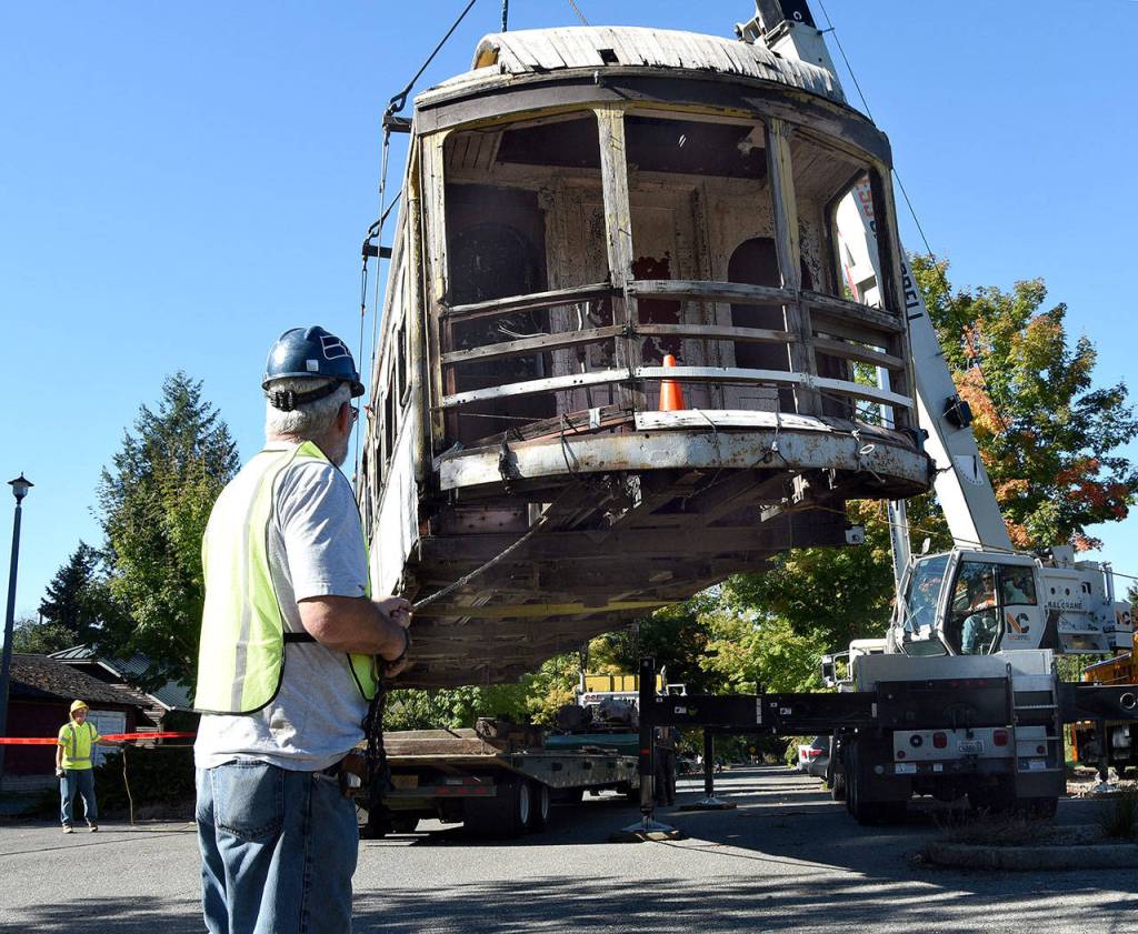 A crane lifts the donated electric car off the flatbed truck that hauled it from Petaluma, CA, and turns to set it on the flatbed train car that will take it to the Northwest Railway Museum&rsquo;s conservation and restoration center. Men hold each corner by a rope so the car doesn&rsquo;t spin. (Carol Ladwig/Staff Photo)