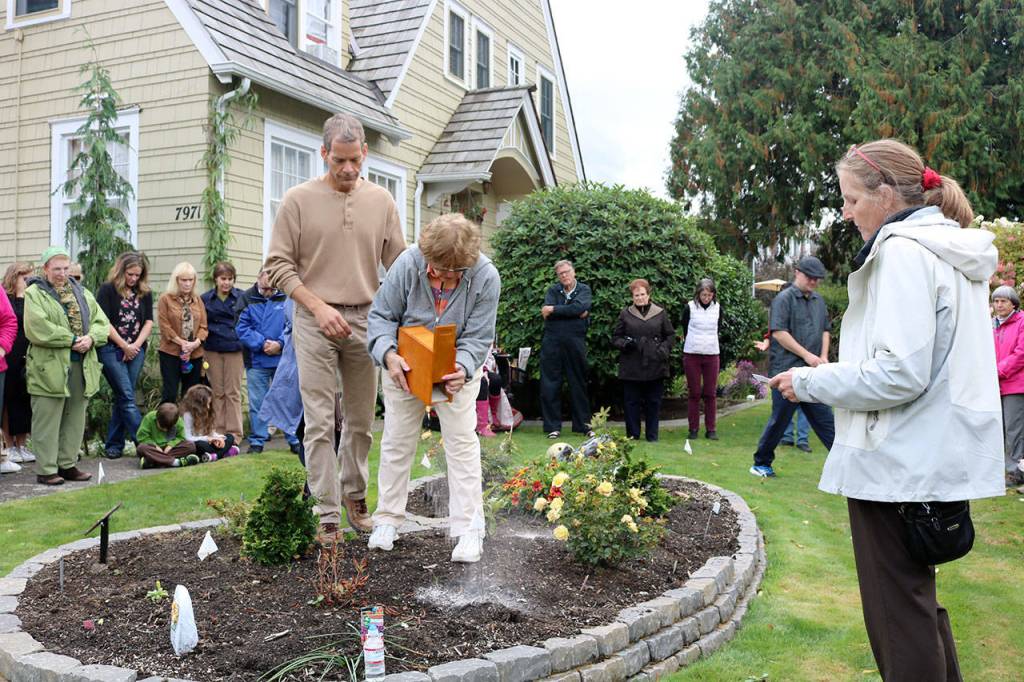 Carol and her son Ryan spread some of Charles&rsquo; ashes on the memorial garden, while Pastor Lee Carney Hartman (Evan Pappas/Staff Photo)