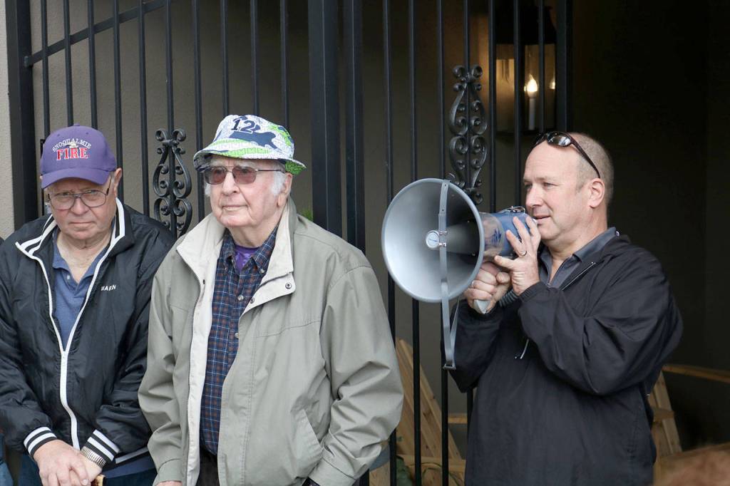 Russell Wentz speaks about the history of the siren before passing the megaphone to Lee Briggs, middle, at the Charles Peterson memorial event on Oct. 1. (Evan Pappas/Staff Photo)