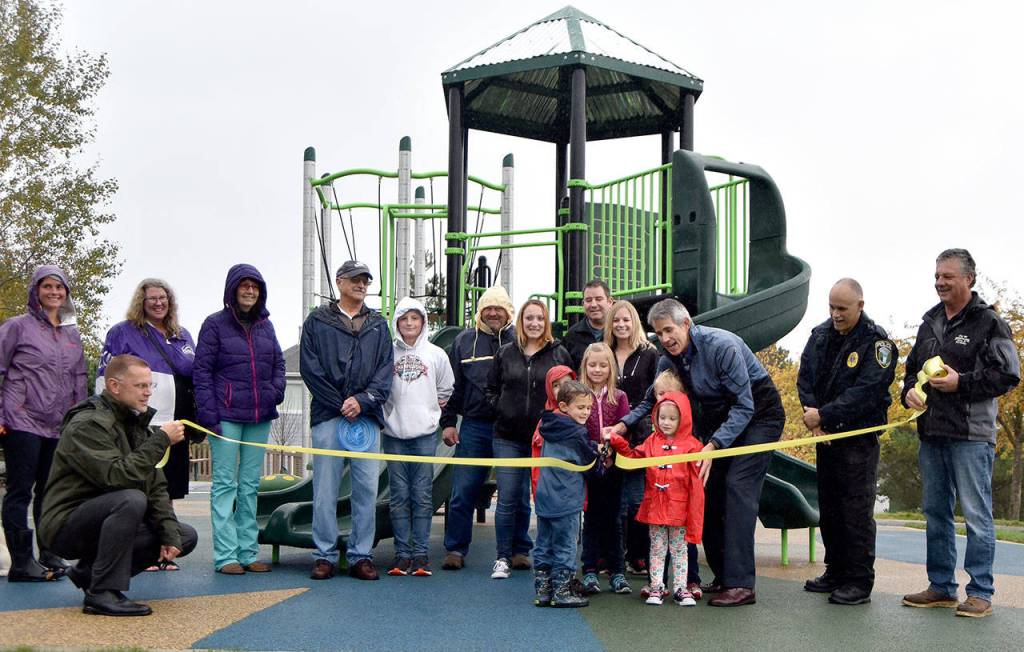 Parents, children and city staff gathered to cut the ribbon on the new playground equipment and surface installed at Ironwood Park, Wednesday, Oct. 25. The improvements were part of the city&rsquo;s capital improvements plan. (Carol Ladwig/Staff Photo)