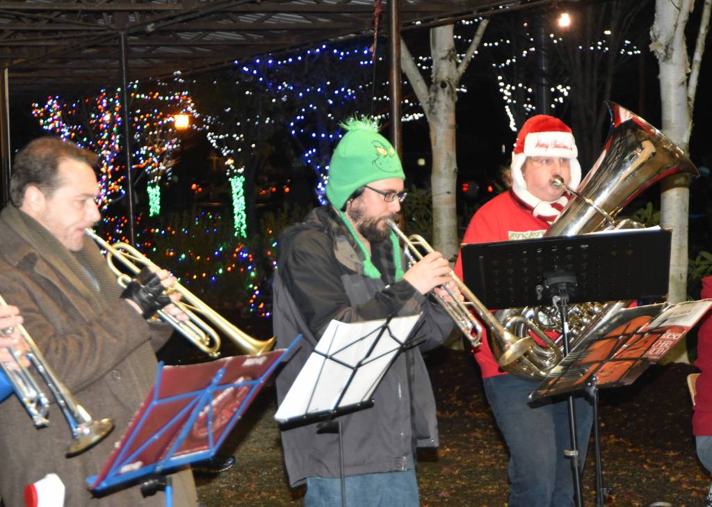 Sno Valley Winds musicians Erik Dickerson, center, and Erik Thurston performed for Saturdays tree lighting in Snoqualmie in holiday themed hats, the Grinch and Santa, respectively. (File Photo)