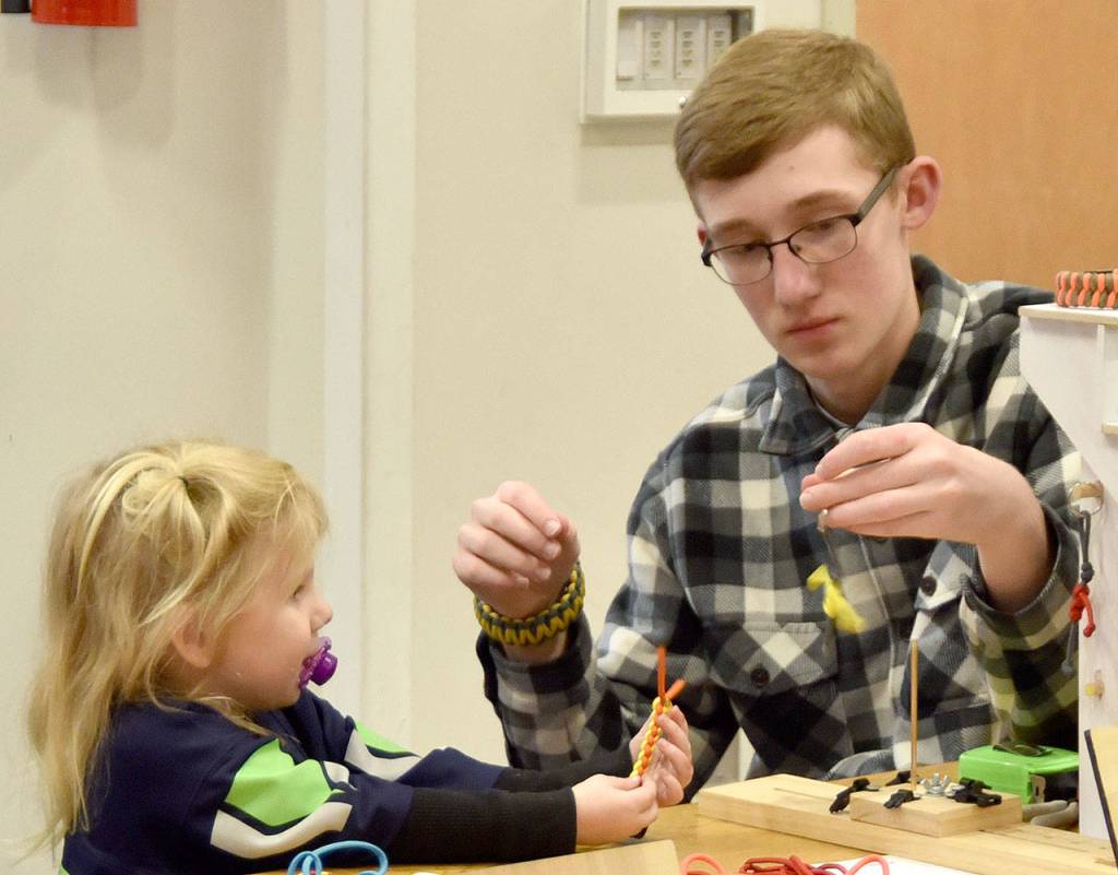 Presley Travis, age 3 and a half, and Brandon Wilhite work on paracord creations at their booth at the Fall City Holiday Market Saturday. (Carol Ladwig/Staff Photo)