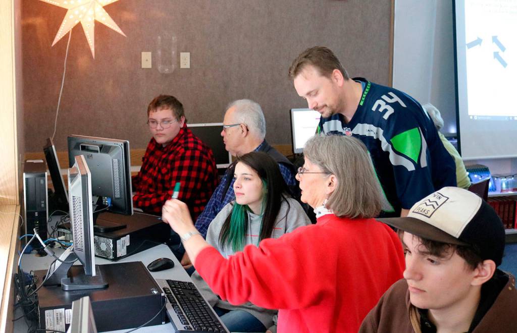 Brianna Dreifus and Donna Driver get help from history teacher Charlie Kroiss. (Evan Pappas/Staff Photo)