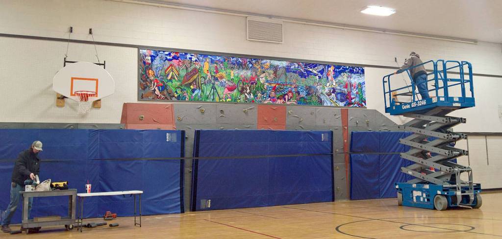 School district maintenance workers install the mural above the Opstad gyms rock wall on Dec. 28. (Courtesy Photo)