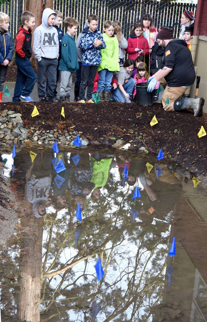 Water pools in the site that will soon become Carnation Elementary Schools rain garden, while students learn the basics of plants and erosion. (Carol Ladwig/Staff Photo)