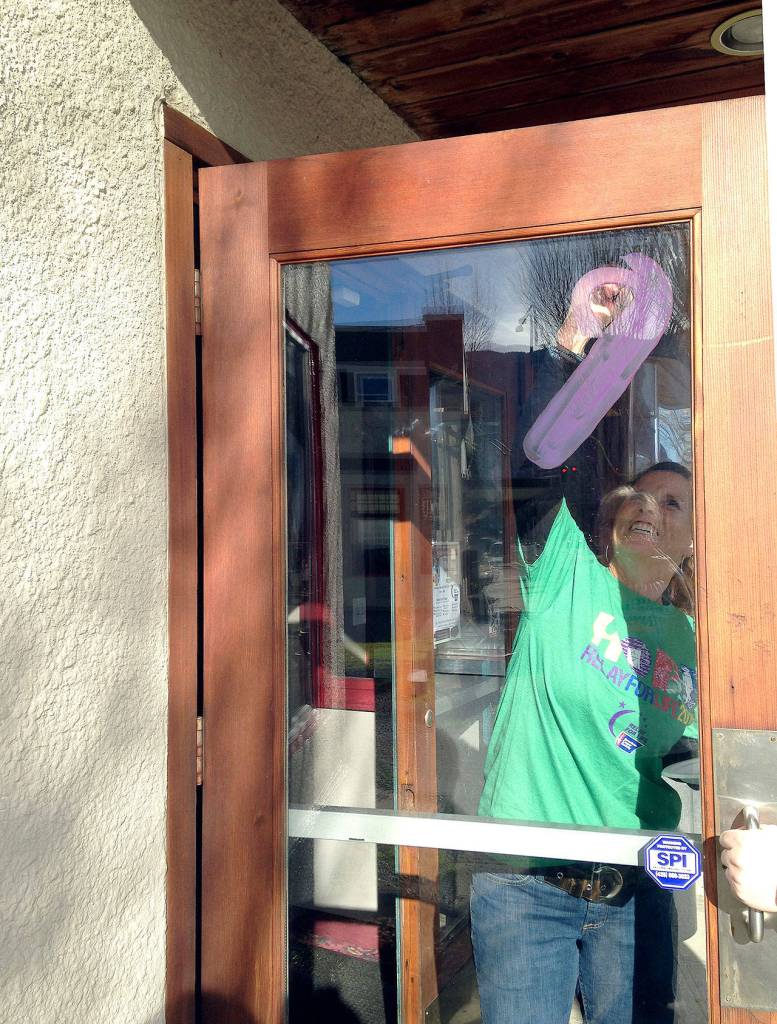 Relay for Life volunteer Sharon Piper paints the North Bend Theatres doors in 2015 as part of the fundraisers Paint the Valley purple campaign. (Record file photo)