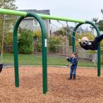 Snoqualmie Police Chief Perry Phipps watches as youngsters Mitchell Collins and Nicholas Geib try out the new swingset at the Oct. 25, 2017 ribbon cutting for the new Ironwood Park. Community involvement is an important role for police in Snoqualmie, he said. (Carol Ladwig/Staff Photo)