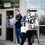 Bellevue High School student Charlie Kern holds a sign calling for more guns, less crime as another student holds a sign that reads books, not bullets. The walkout was student-led and students were able share their opinions and have a dialogue with one another. Raechel Dawson/staff photo