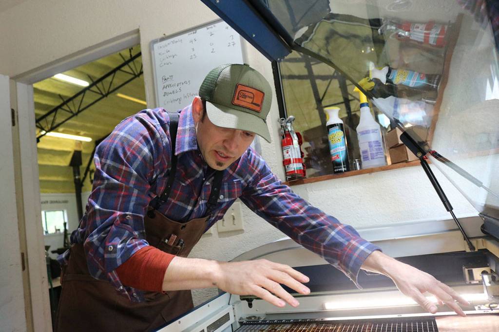 Jeb Haber arranges strips of leather on his laser cutting machine which etches designs from raw materials to be used in craft kits. Aaron Kunkler/Staff photo