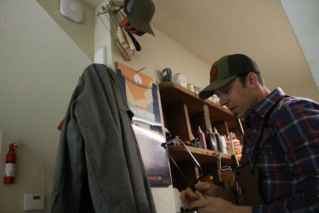 TogetherMade owner Jeb Haber selects a wood saw from his wall to work on a wooden pocket knife kit which he manufacturers. Aaron Kunkler/Staff photo