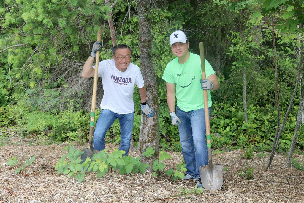 Haru and Joshua Morisawa clean up an area by a tree at Stillwater Bog. Evan Pappas/Staff Photo