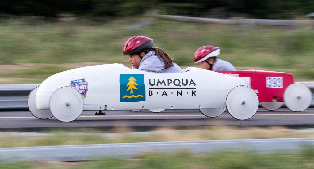 Amelia Allen (left) looks down at the track as she races another driver in unweighted practice soap box derby cars June 7 on Camano Island. The 11th Stanwood-Camano Soap Box Derby takes place Saturday. (Andy Bronson / The Herald)