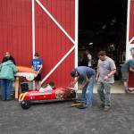 Parents and kids prep soap box derby cars outside the barn. (Andy Bronson / The Herald)