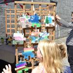 Susan OMalley hangs painted puzzle pieces to dry at the Mount Si Artist Guild booth Saturday during the Block Party. The pieces, painted by children as an arts activity, will be assembled into a community collage, OMalley said. Carol Ladwig/Staff Photo