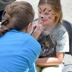 Shayne Dickelman smiles as Encompass face painter Emily Creed transforms her into a tiger Saturday during the Block Party. Carol Ladwig/Staff Photo