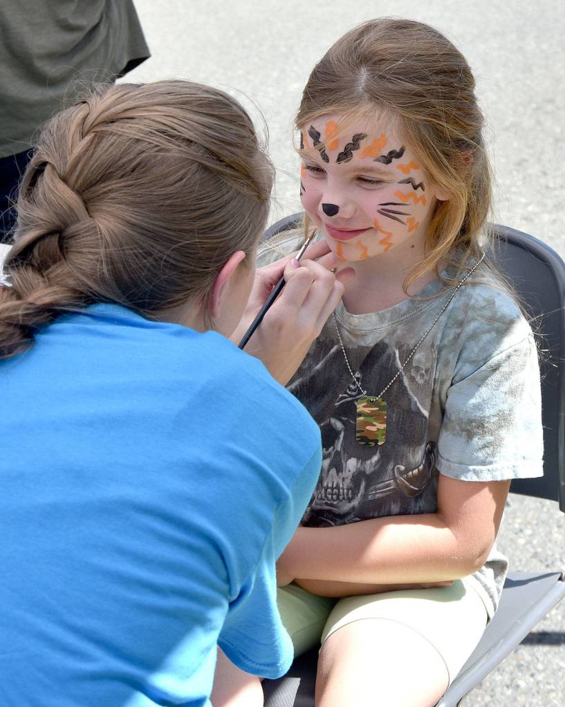 Shayne Dickelman smiles as Encompass face painter Emily Creed transforms her into a tiger Saturday during the Block Party. Carol Ladwig/Staff Photo